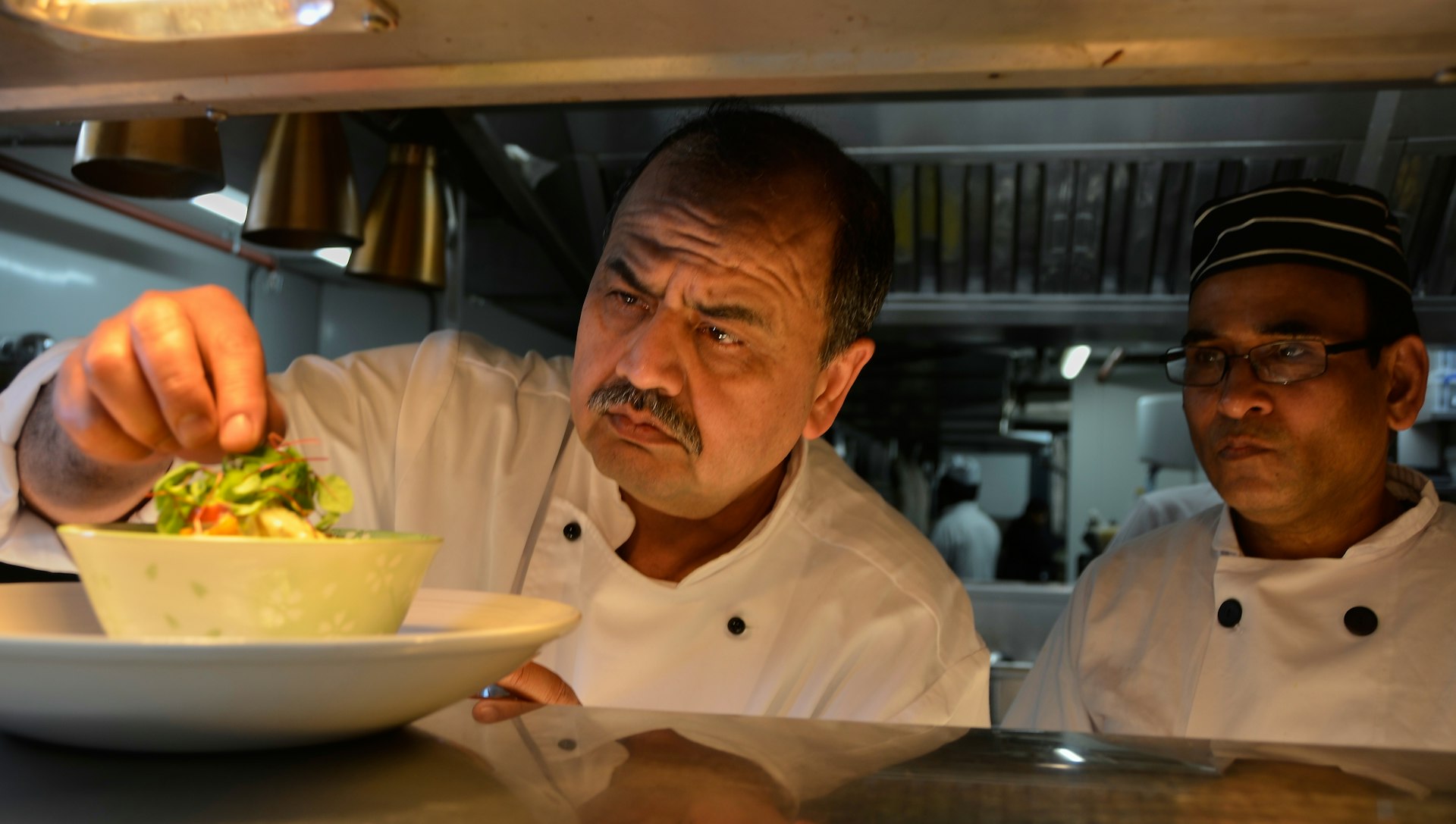 two chefs in a kitchen preparing a meal